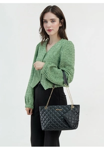 Detailed view of black quilted tote bag set with gold chain strap and mini purse pendant