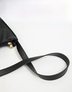 Detailed macro of black lychee grain texture and gold zipper on a large shoulder bag
