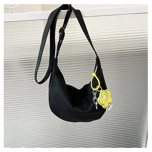 Détail du sac bandoulière demi-lune noir avec charm fleur jaune et chaîne acrylique