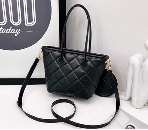 Detail of black quilted tote bag featuring gold hardware and a matching round coin purse