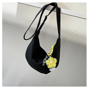 Détail du sac bandoulière croissant noir avec un pendentif fleur de tournesol