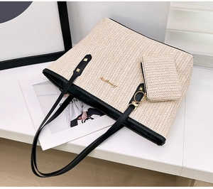 Detail of woven straw tote bag set with black leather handles and gold rivet accents
