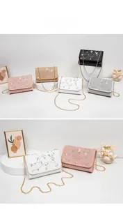 Close-up of floral embroidery on leather crossbody bags with gold chain straps in five colors
