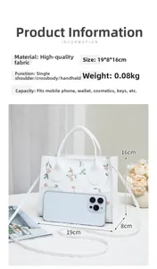 Detail view of white handbag with pink floral embroidery and 19x8x16cm dimensions