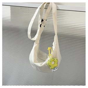 Détail du sac demi-lune en toile beige avec charm fleur jaune et bandoulière large