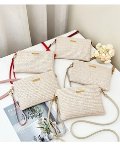 Detail of woven straw envelope bags featuring gold metal plate and colorful leather straps
