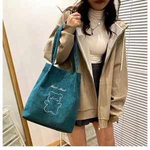 Dettaglio della borsa tote in velluto a coste verde scuro con ricamo a forma di orso