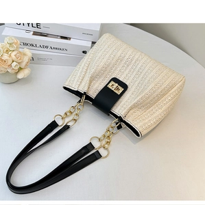 Detail of woven beige texture with black leather strap and gold metal turn-lock closure