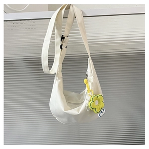 Détail du sac croissant en toile blanche avec bandoulière large et pendentif fleur jaune