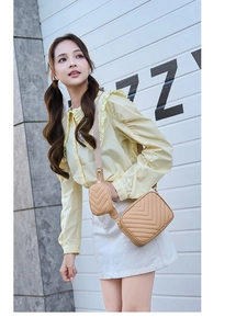 Detail of apricot V-quilted crossbody bag with small round coin purse and gold zippers