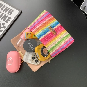 Colorful striped woven crossbody bag with gold buckle on a black surface in flat lay view