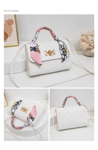 Detail view of white quilted crossbody bag with gold twist lock and floral scarf handle