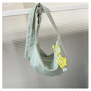 Détail du sac bandoulière demi-lune vert menthe avec texture côtelée et breloque fleurie