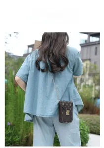 Outdoor shot of a vintage pattern mini crossbody phone bag with gold chain and clasp