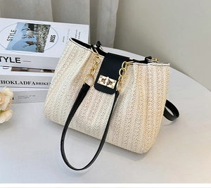 Detail of cream woven bucket bag featuring black leather trim and gold twist lock