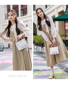 Detail of embroidered floral patterns on a white handbag with model in street setting