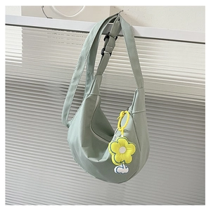 Détail du sac croissant en velours côtelé vert clair avec sangle et breloque tournesol