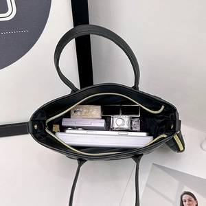 Minimalist black quilted tote bag with gold zipper showing spacious interior storage
