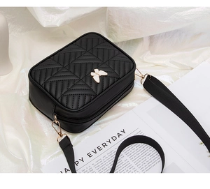Detailed shot of black quilted crossbody bag with butterfly buckle on silk cloth