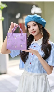 Close-up of a purple handbag featuring delicate pink floral embroidery on smooth leather