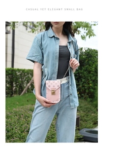 Pink monogram mobile phone bag with golden chain strap and buckle shown on a model