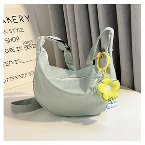 Détail du sac croissant plissé vert clair avec breloque fleur jaune et bandoulière