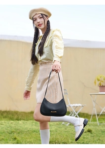 Close-up of black lychee grain texture and gold logo on women's crescent underarm bag