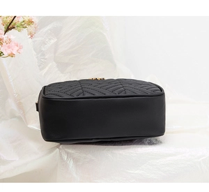 Detail showing the bottom and side of a black quilted crossbody bag with gold hardware