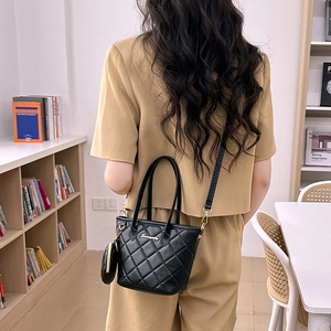 Quilted black bucket bag with dual handles and mini round pouch charm for women