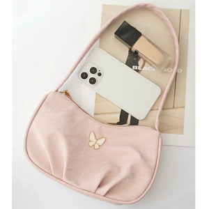 Pink pleated underarm bag with butterfly ornament placed on a fashion magazine