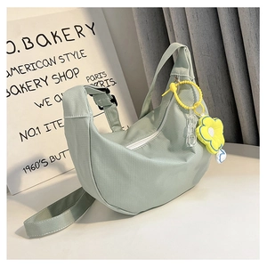 Détail du sac hobo vert menthe avec texture rayée et charmant pendentif fleur jaune