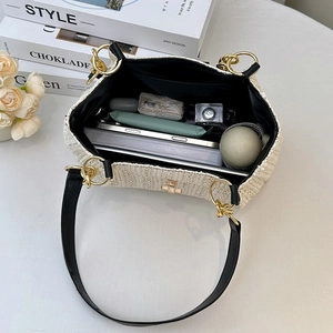 Large cream straw bucket bag with black leather handles showing spacious interior capacity