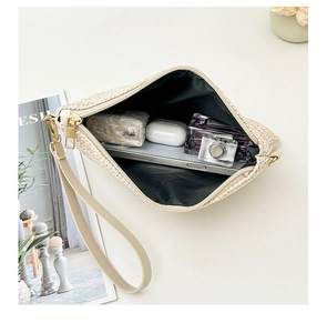 Detail of woven straw clutch bag showing spacious interior for phone and accessories