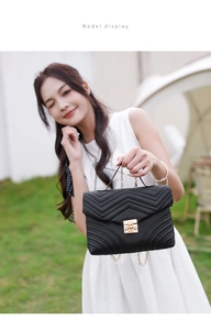 Outdoor model shot of black quilted crossbody bag with golden clasp and chain strap