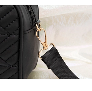 Macro shot of black quilted faux leather bag featuring shiny gold hardware and metal hooks