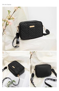 Detailed view of black quilted crossbody bag with golden metal plate and wide lettered strap