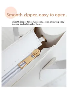 Close-up of smooth gold-tone zipper and fine stitching on white leather handbag detail