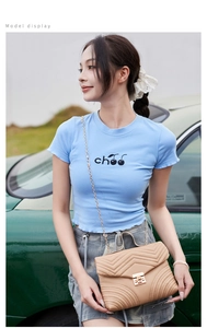 Detail of light blue cherry print crop top with wavy hem and quilted chain crossbody bag