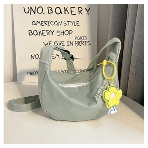 Détail du sac demi-lune vert menthe avec tissu micro-ridé et breloque fleur jaune