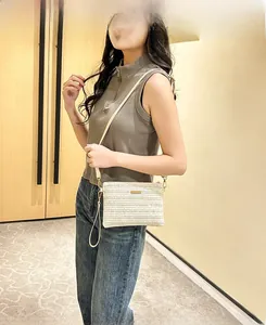 Detail of the woven shoulder bag showing golden metal accents and cream texture