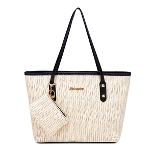 Large beige woven straw tote bag set with black leather straps and gold logo detail