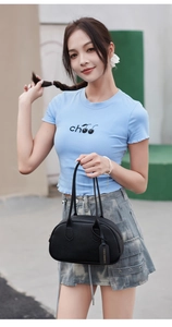 Detail of black pebbled leather handbag with double handles and fashion brand hangtag