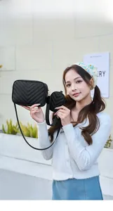Detail of black V-quilted crossbody bag with a detachable coin purse and gold hardware