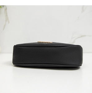 Close-up of black lychee textured leather bag featuring golden metal logo lettering