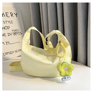 Détail du sac à bandoulière en tissu plissé crème avec un pendentif fleur jaune