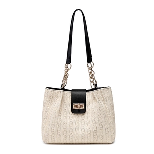Straw bucket bag with black leather straps and gold metal lock on white background
