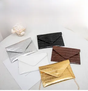 Flat lay of envelope clutch bags in five colors with textured crocodile pattern and gold chains