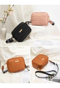 Detailed close-up of quilted crossbody bag featuring metal plate and graphic wide strap