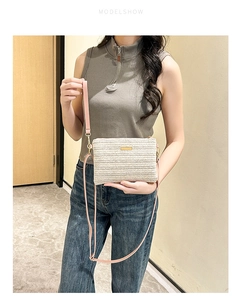 Détail d'un sac à bandoulière tissé blanc cassé avec boucle dorée et lanière rose