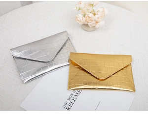 Detail of silver and gold envelope clutch bags with luxury crocodile embossing texture